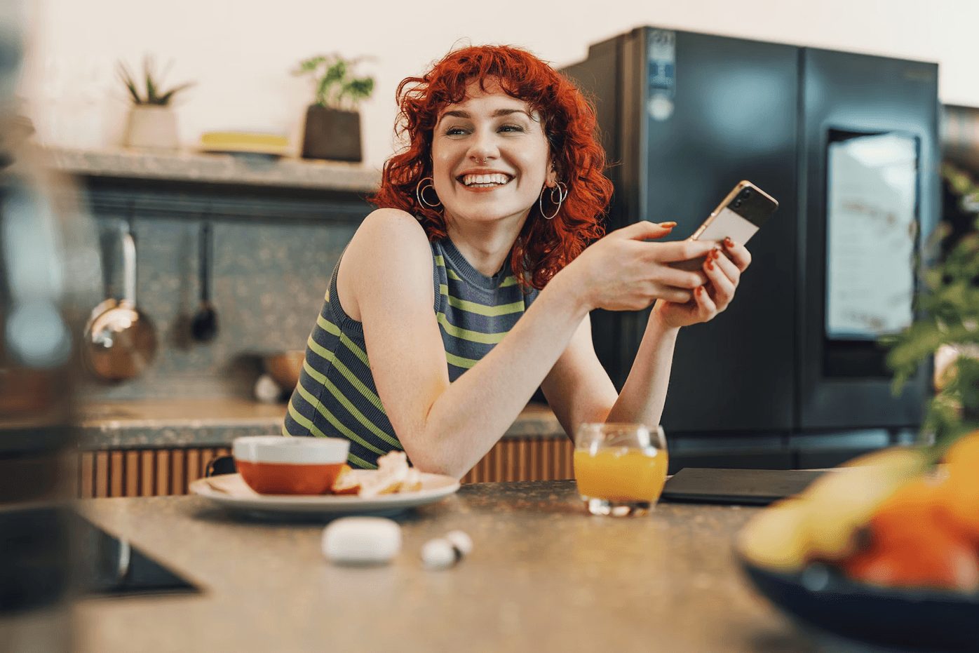 Two friends checking a store offer on a phone at a kitchen table